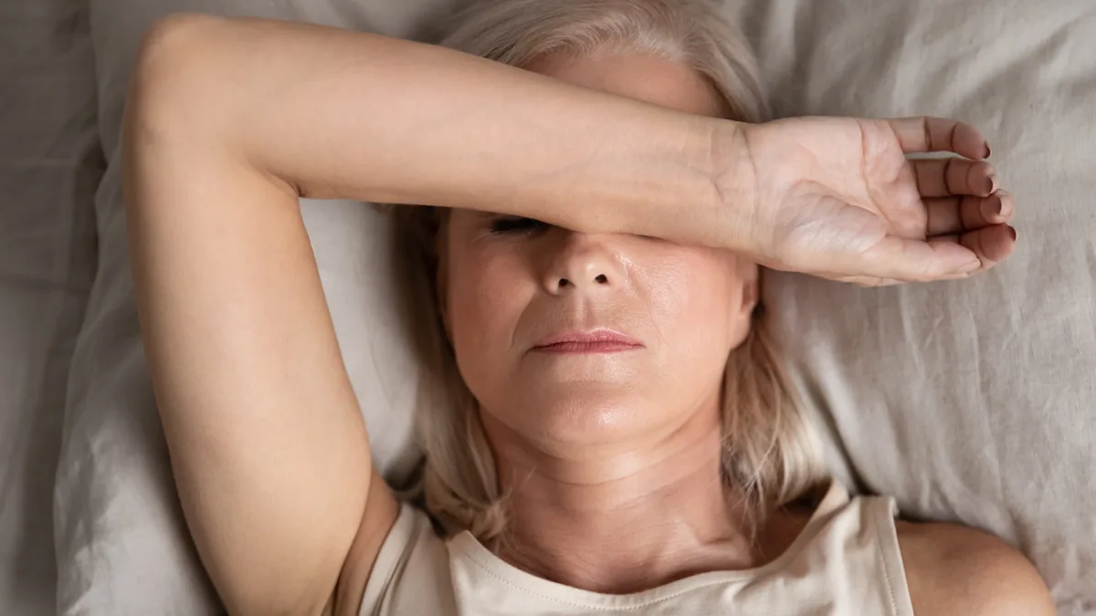 Woman lying on a pillow with her hand on her forehead